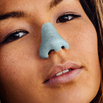 Load image into Gallery viewer, eye level close up image of young woman face wearing Nöz blue color sunscreen coated on nose 
